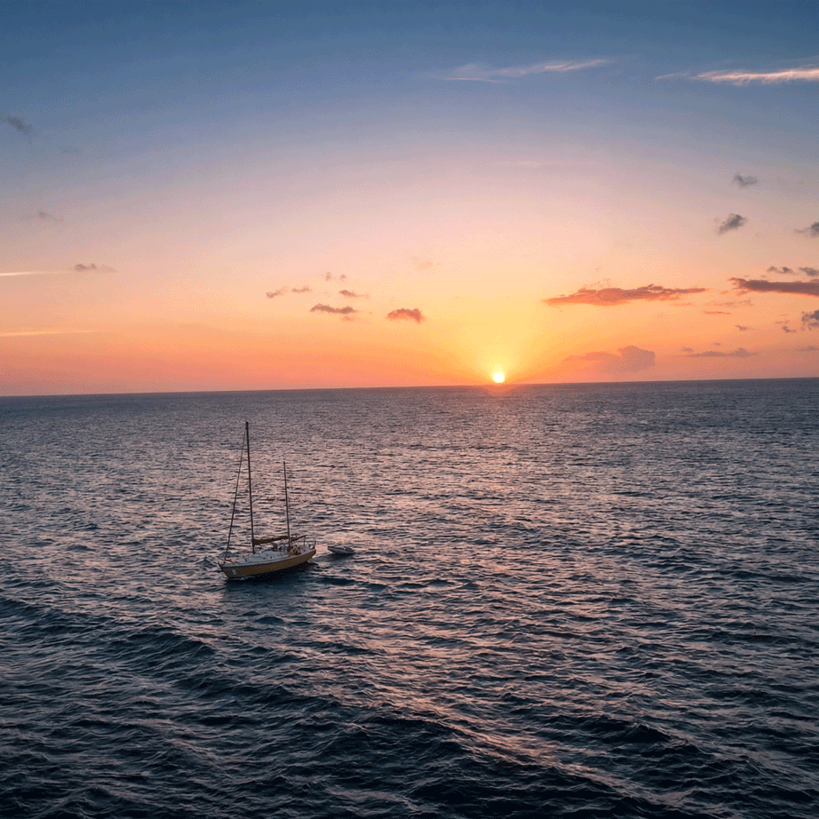 Voilier à l'ancre au large pendant le coucher de soleil sur la mer, à Curaçao.