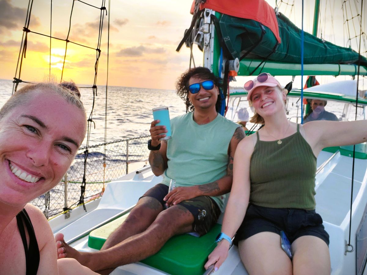 Passagers trinquant à bord du voilier au coucher du soleil, croisière privée à Curaçao.
