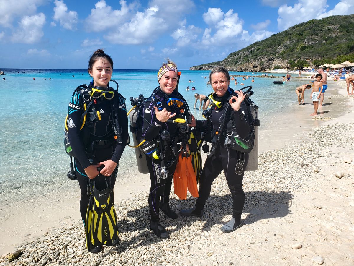 Trois participantes en combinaison prêtes pour leur baptême de plongée, Curaçao.