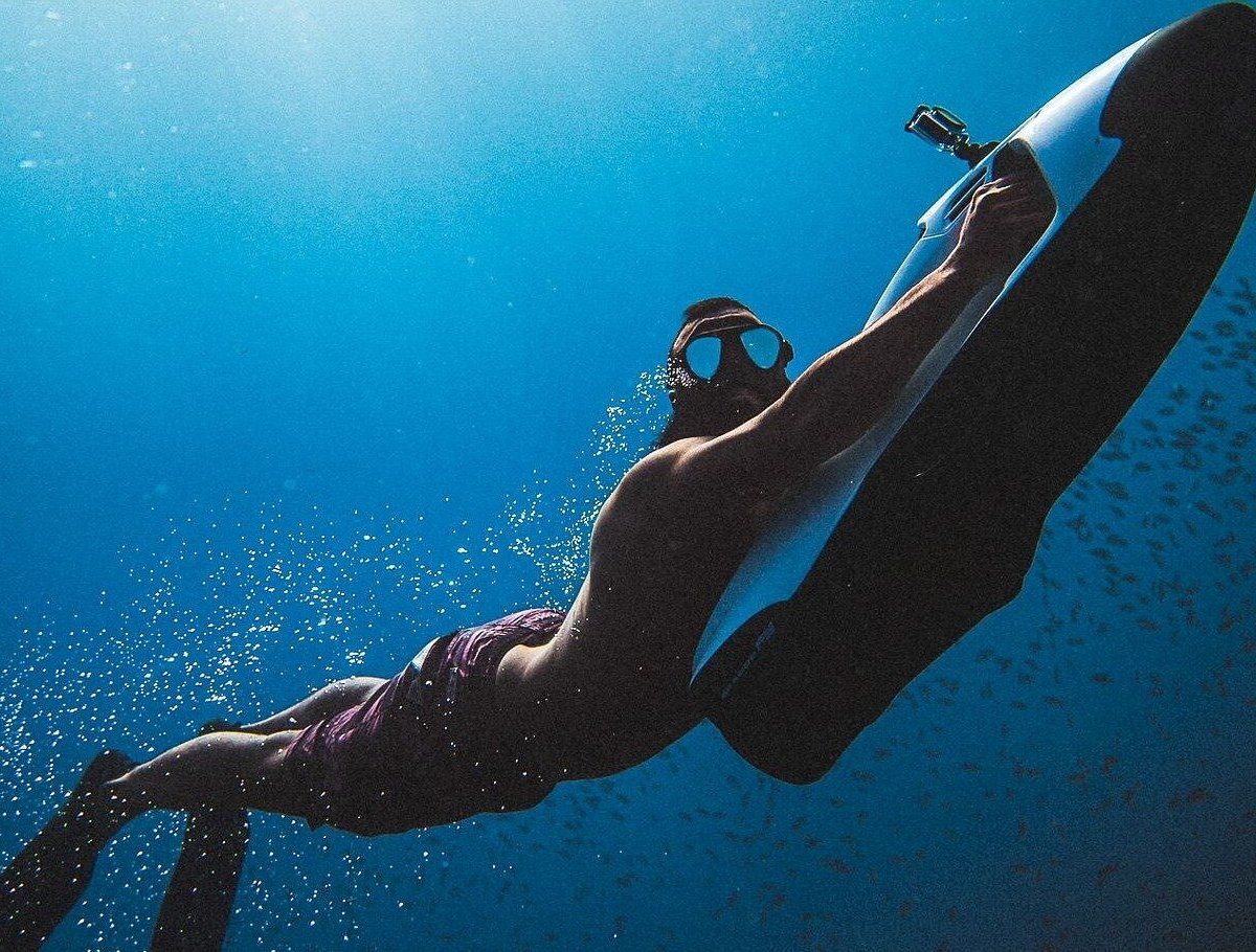 Nageur propulsé par un SeaBob dans l'eau bleue profonde, à Curaçao.