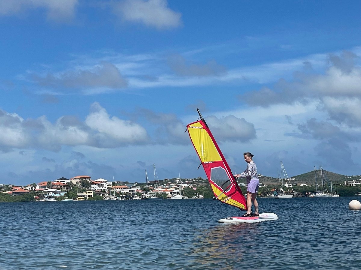 Planchiste à voile glissant devant la côte et les voiliers de Curaçao.