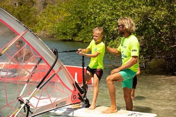 Moniteur expliquant le gréement à un jeune planchiste, cours de planche à voile à Curaçao.