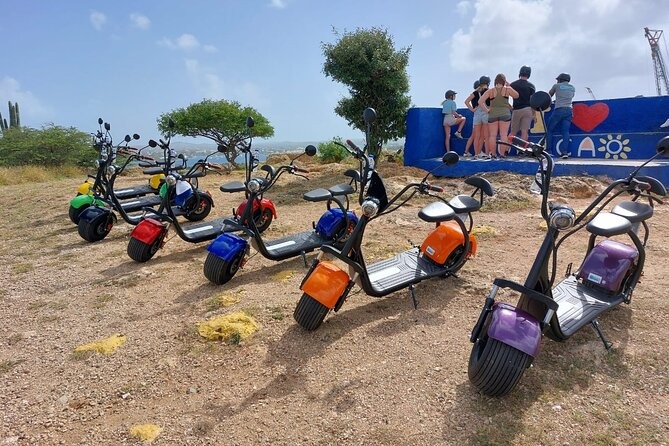 Scooters électriques colorés stationnés près de la côte, tour guidé à Curaçao.