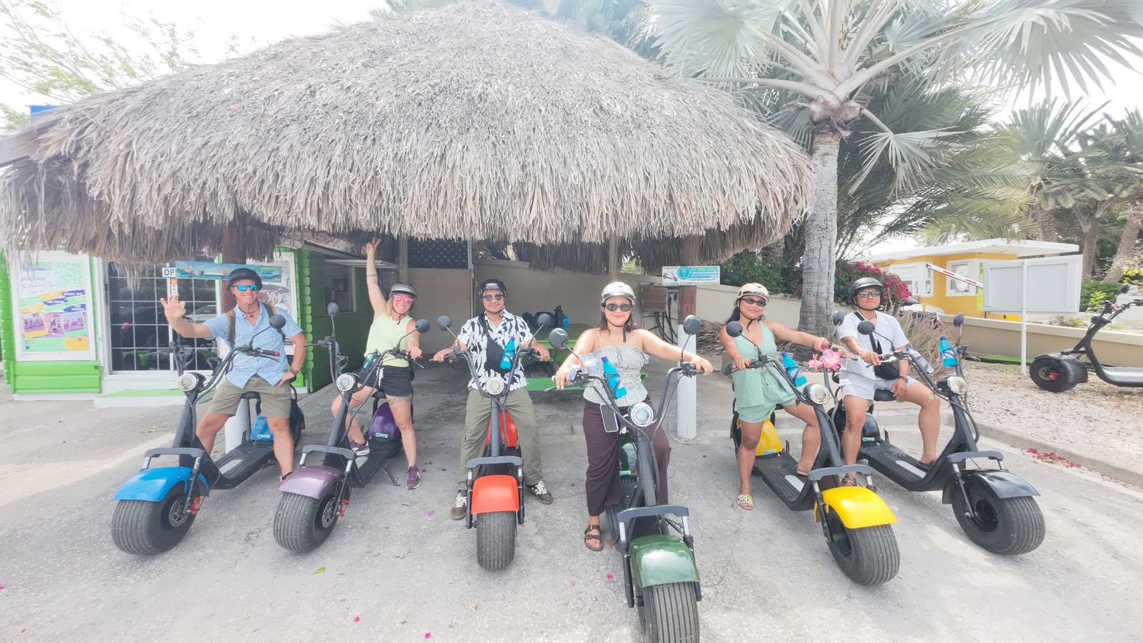 Participants posant avec leurs scooters électriques sous une paillote, à Curaçao.