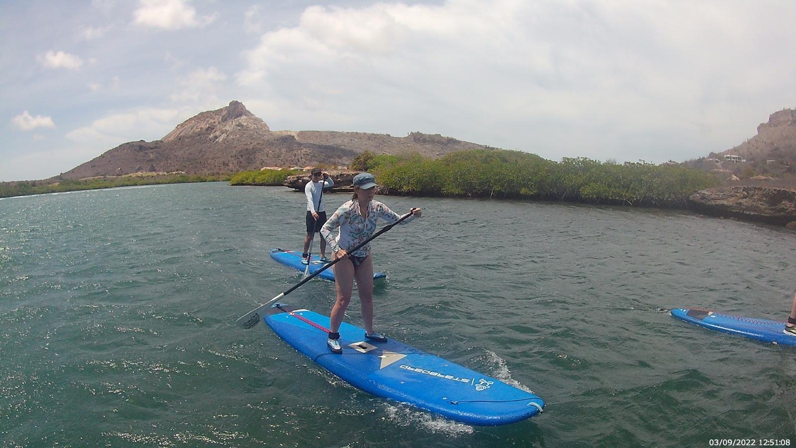 Paddleuse sur une eau calme bordée de mangrove, tour de SUP à Curaçao.